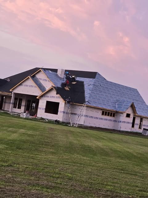 New home construction with roofing at sunset