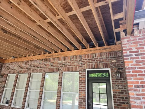 Exposed roof framing on brick home patio extension