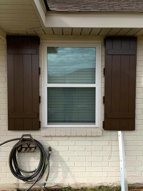 Brown board and batten shutters on brick home
